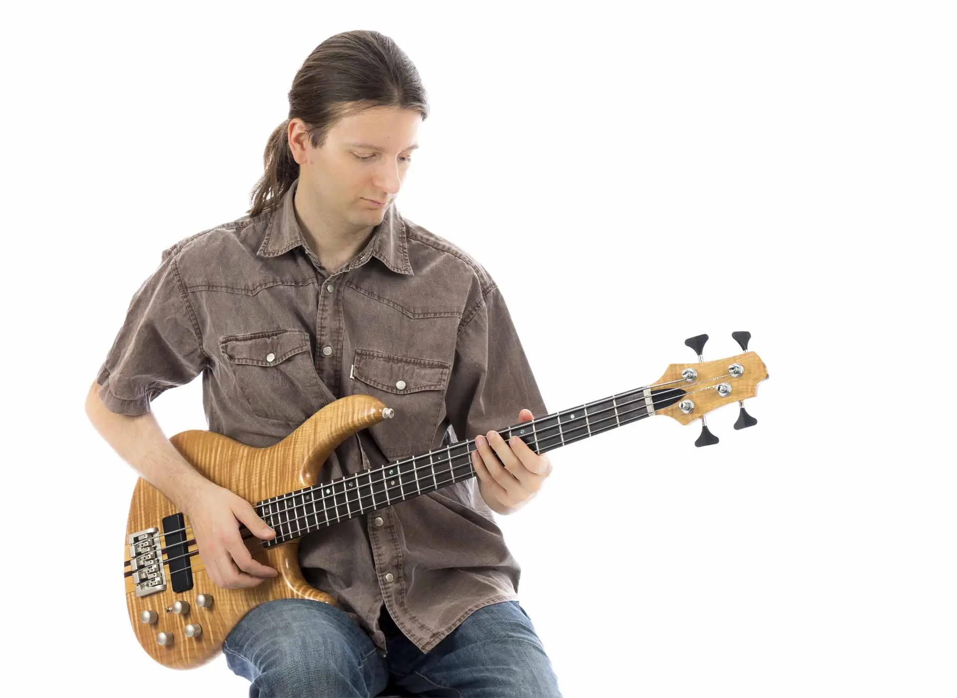 Seated man playing a natural wood bass guitar