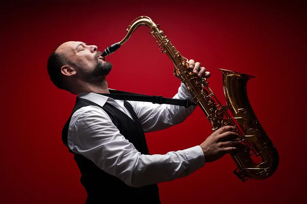 Man playing saxophone against red background