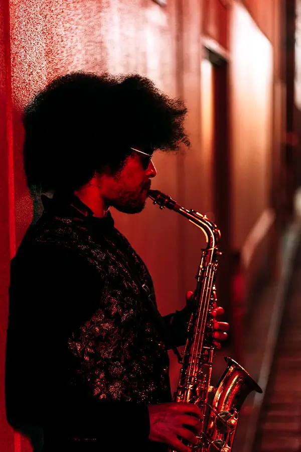 Man leaning against a wall playing a saxophone