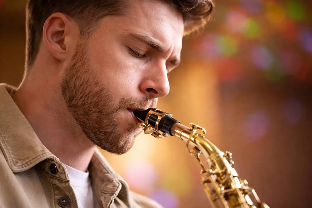 Man playing saxophone in a close-up with a colourful background