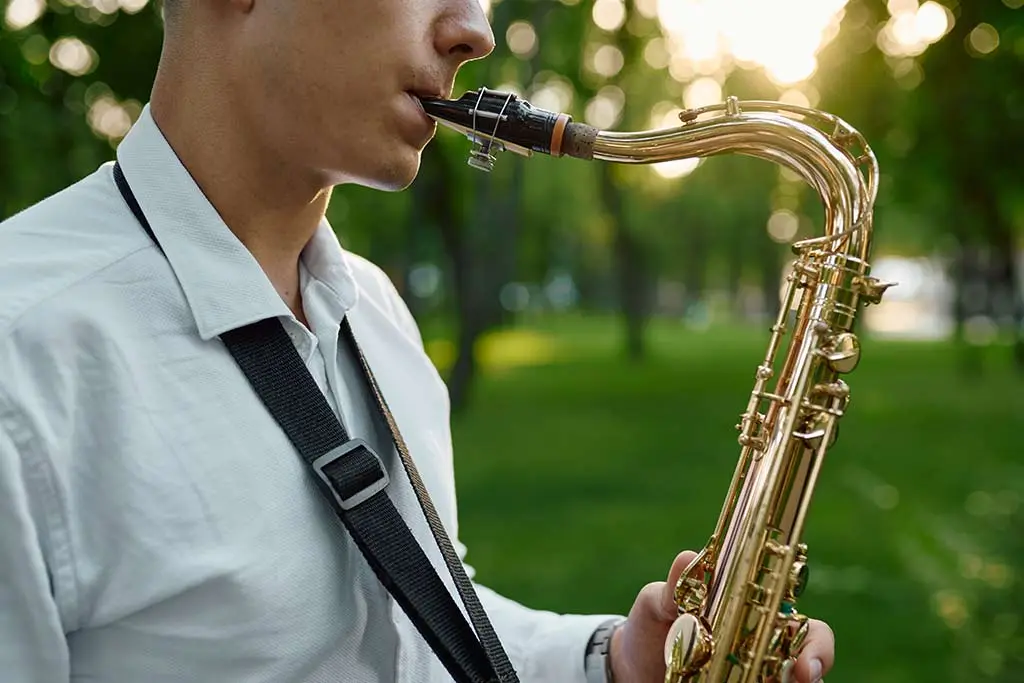 Side view of a man playing saxophone in a park
