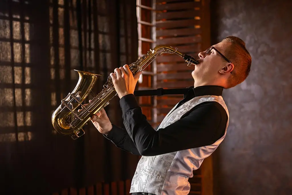 Man leaning back while playing a saxophone indoors