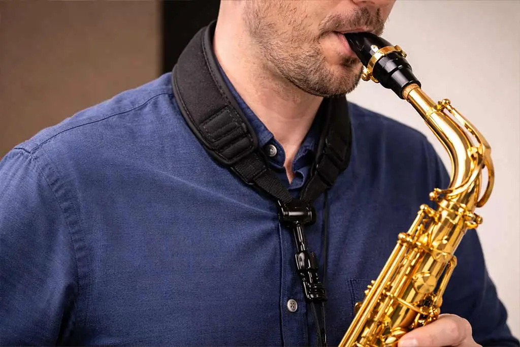 Man playing a saxophone while wearing a neck strap
