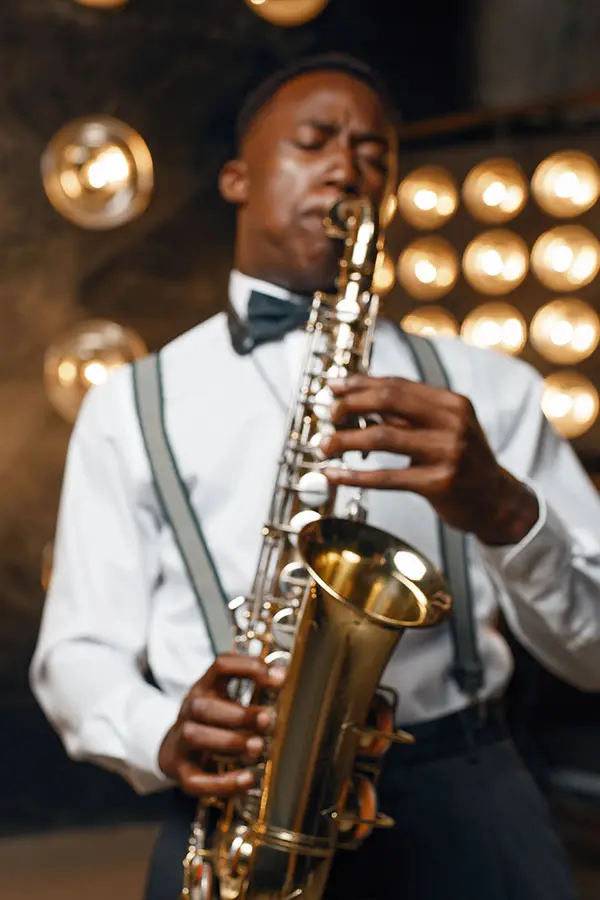 Man in a bow tie playing saxophone under warm lights