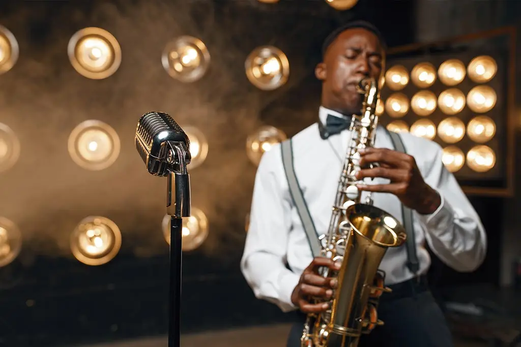 Man playing tenor saxophone beside a vintage microphone