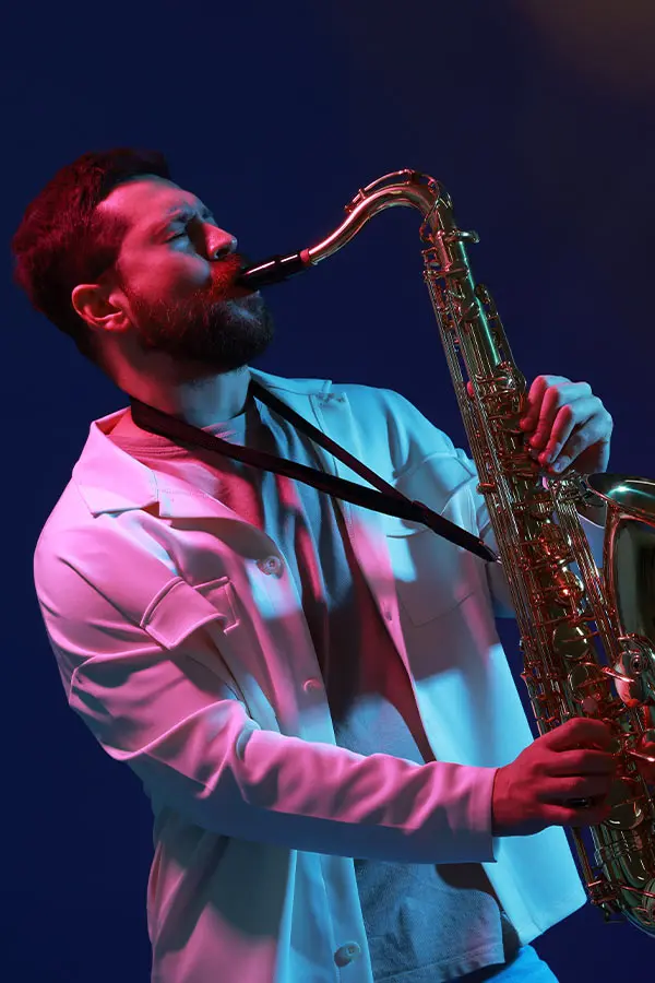 Man in a white jacket playing tenor saxophone on stage