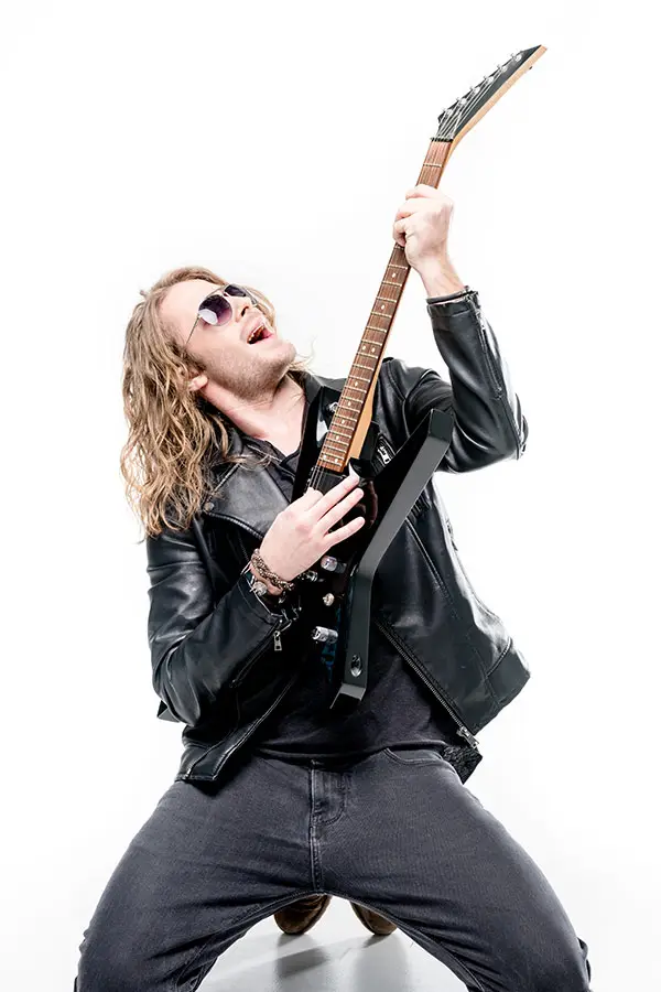 Long-haired man in sunglasses playing a V-shaped electric guitar