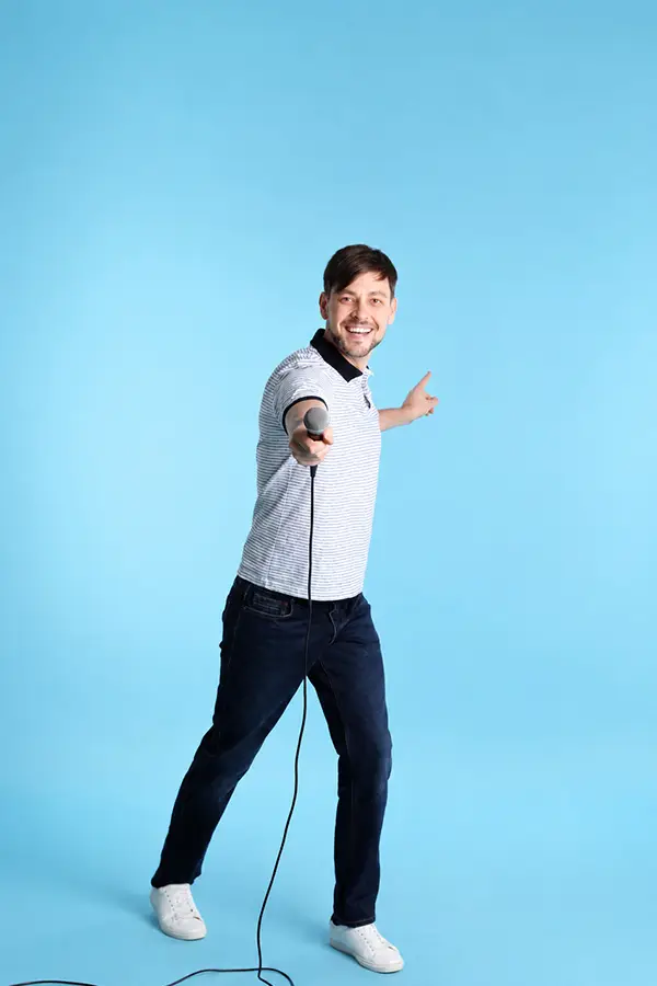 Smiling man pointing while holding a wired microphone