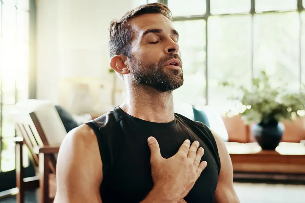 Man practising a breathing exercise with his hand on his chest