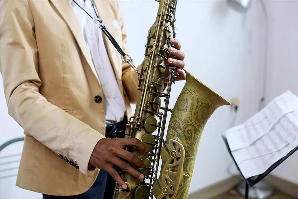 Man practising playing saxophone with sheet music