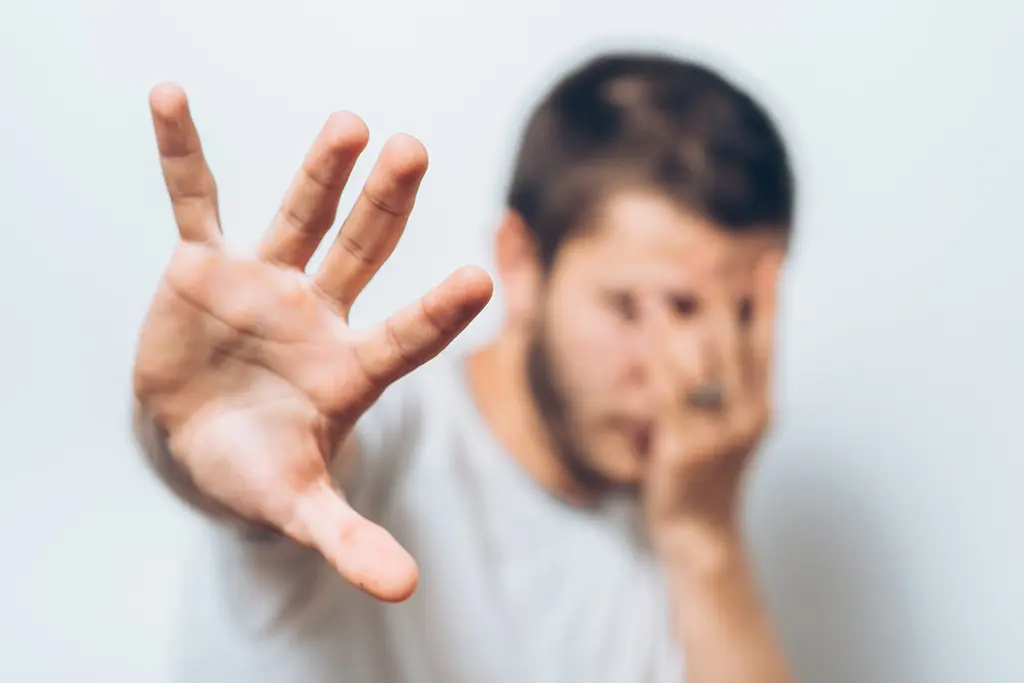 Man raising one hand while covering part of his face