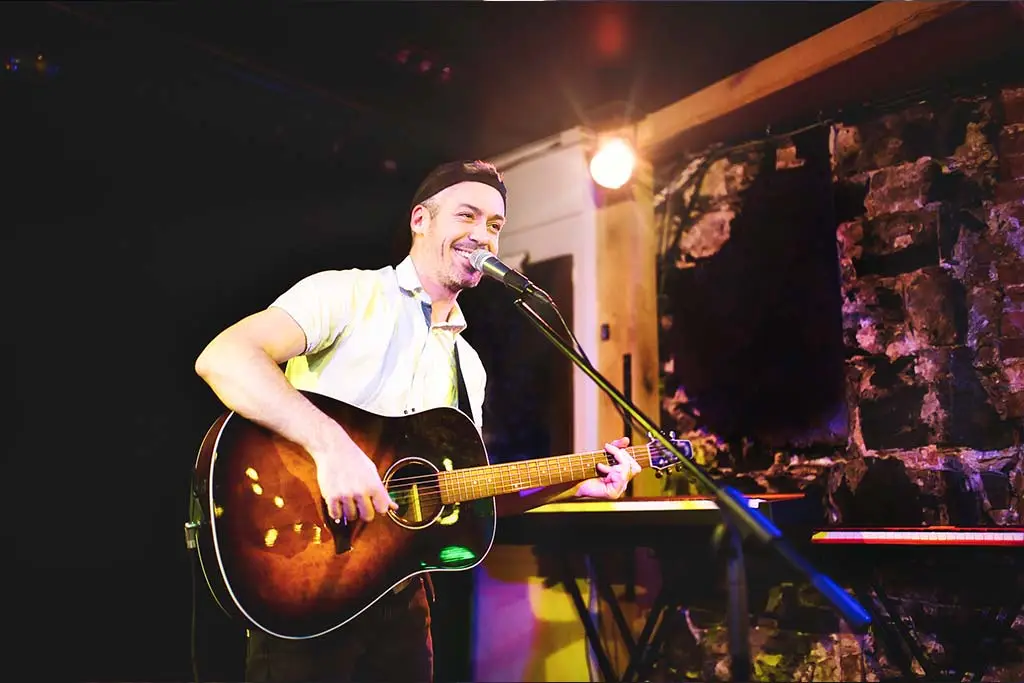 Man singing and playing guitar on stage