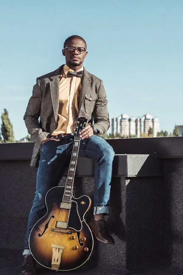 Man sitting outdoors with an archtop electric guitar