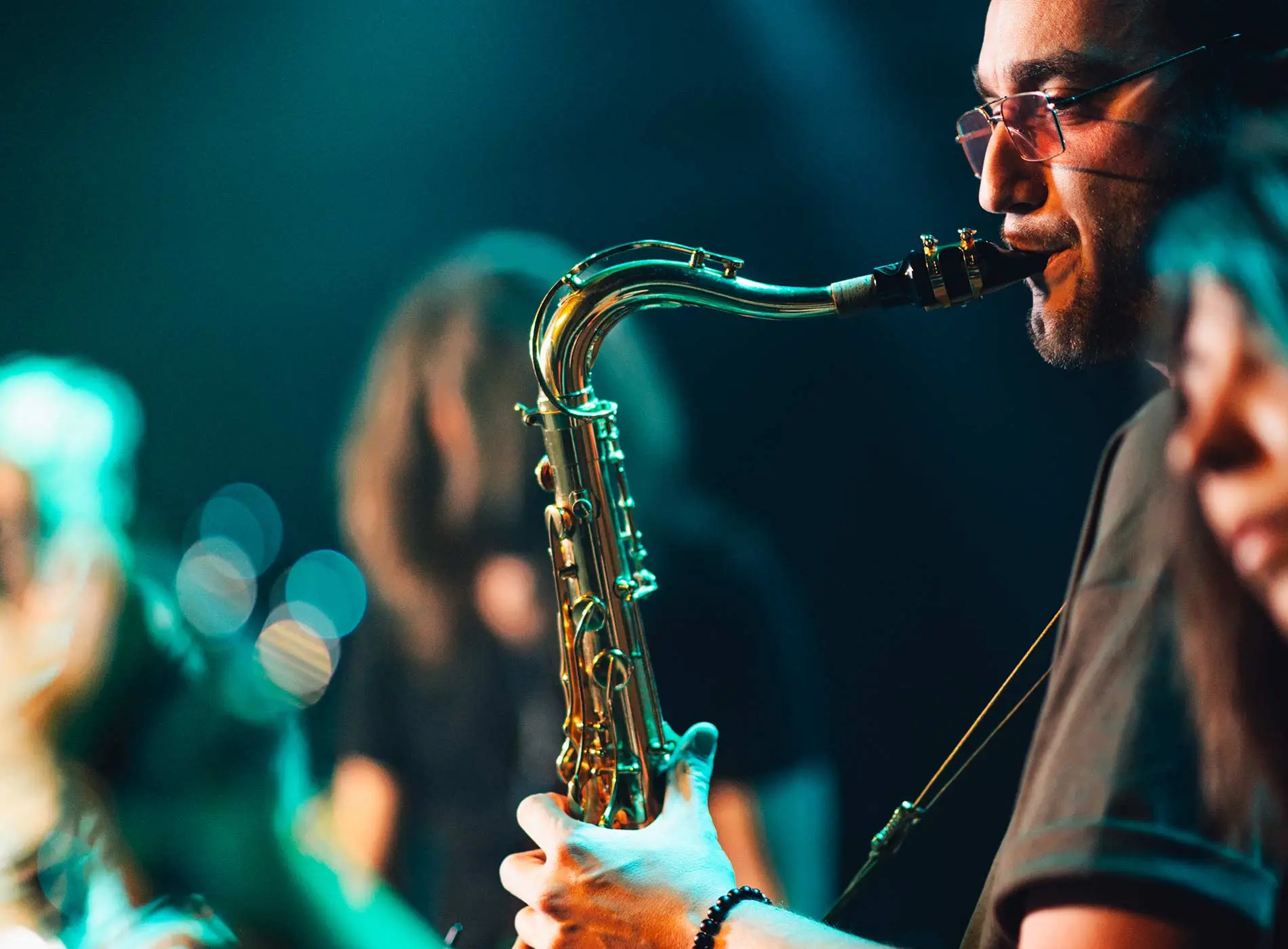 Man with glasses playing saxophone in a band