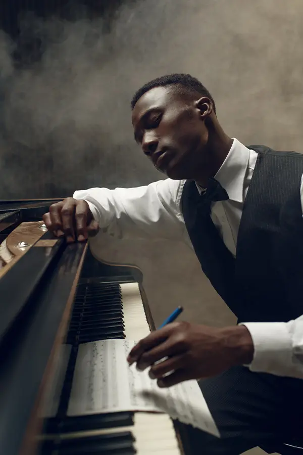 Man in a suit writing music at a piano