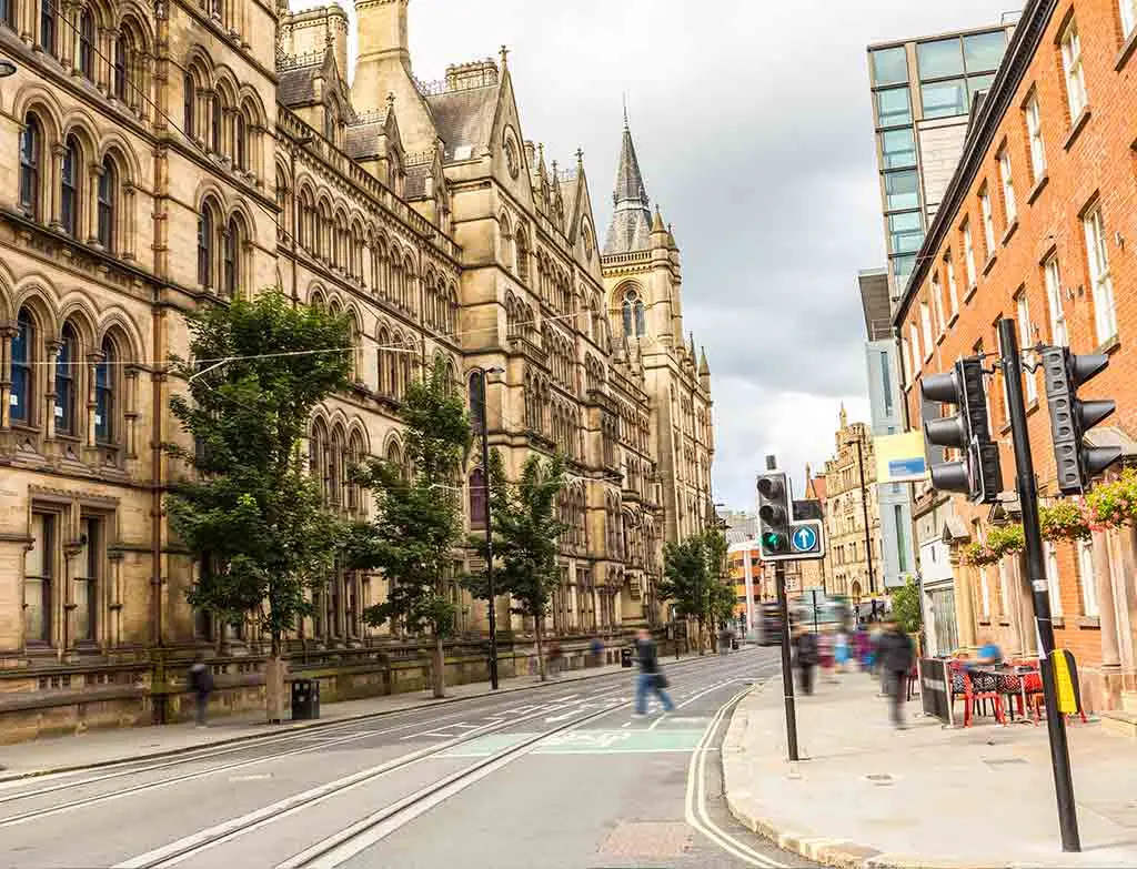 Manchester street with tram tracks and historic stone buildings