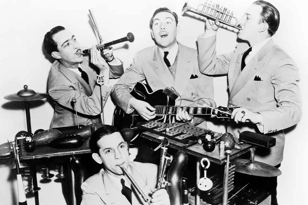 Four men performing with trumpet, electric guitar, saxophone and percussion