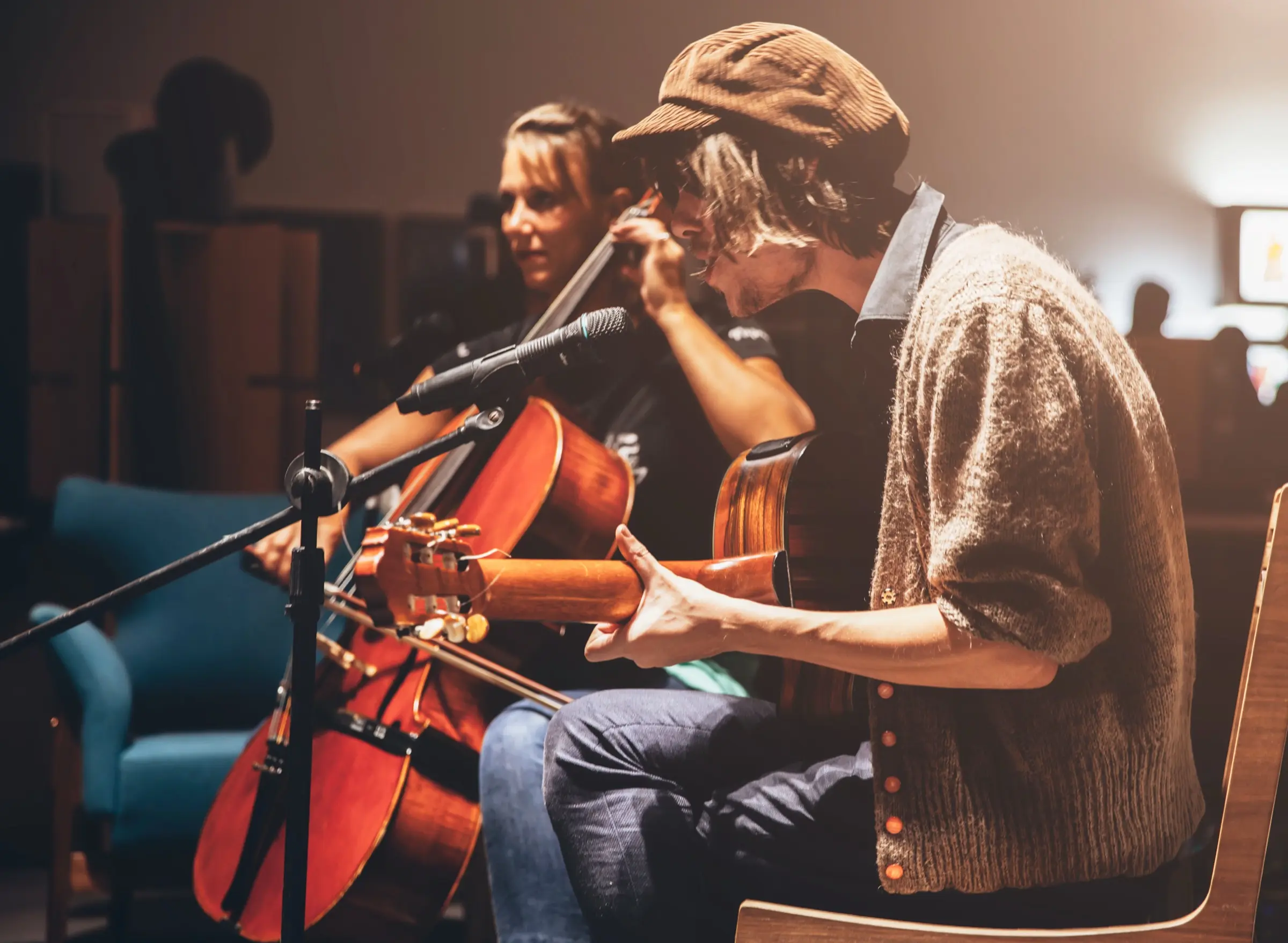 Musicians performing together with a cello, an acoustic guitar and a harmonica.