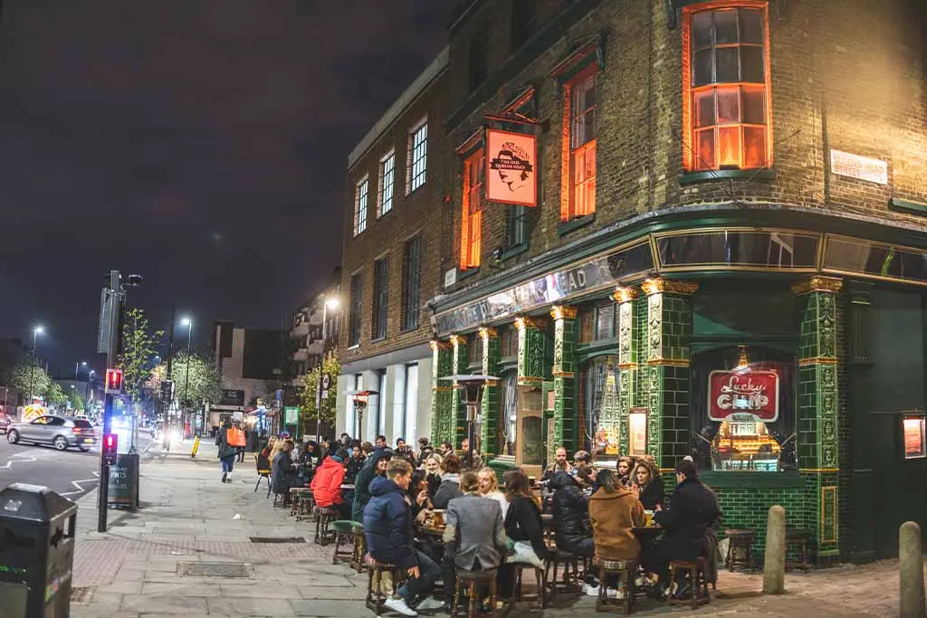 People sitting outside The Old Queen’s Head pub at night