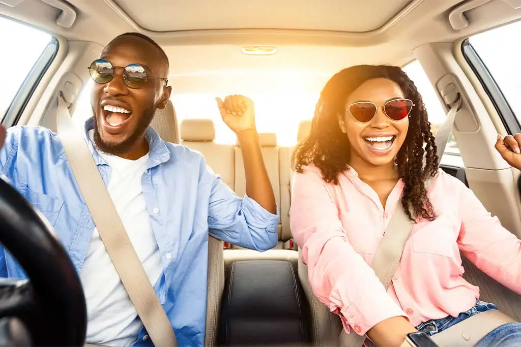 Two people wearing sunglasses singing in a car