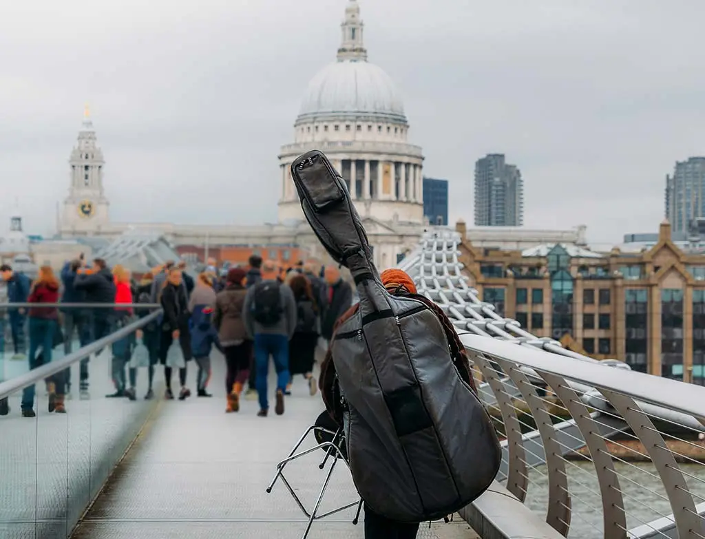 Person carrying a cello case on Millennium Bridge near St Paul's Cathedral