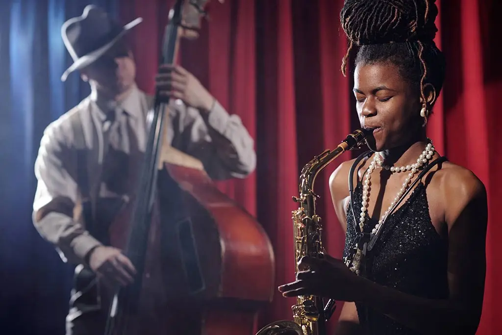 Woman playing saxophone with double bassist on stage