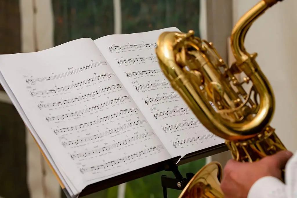 Saxophone held beside an open book of sheet music