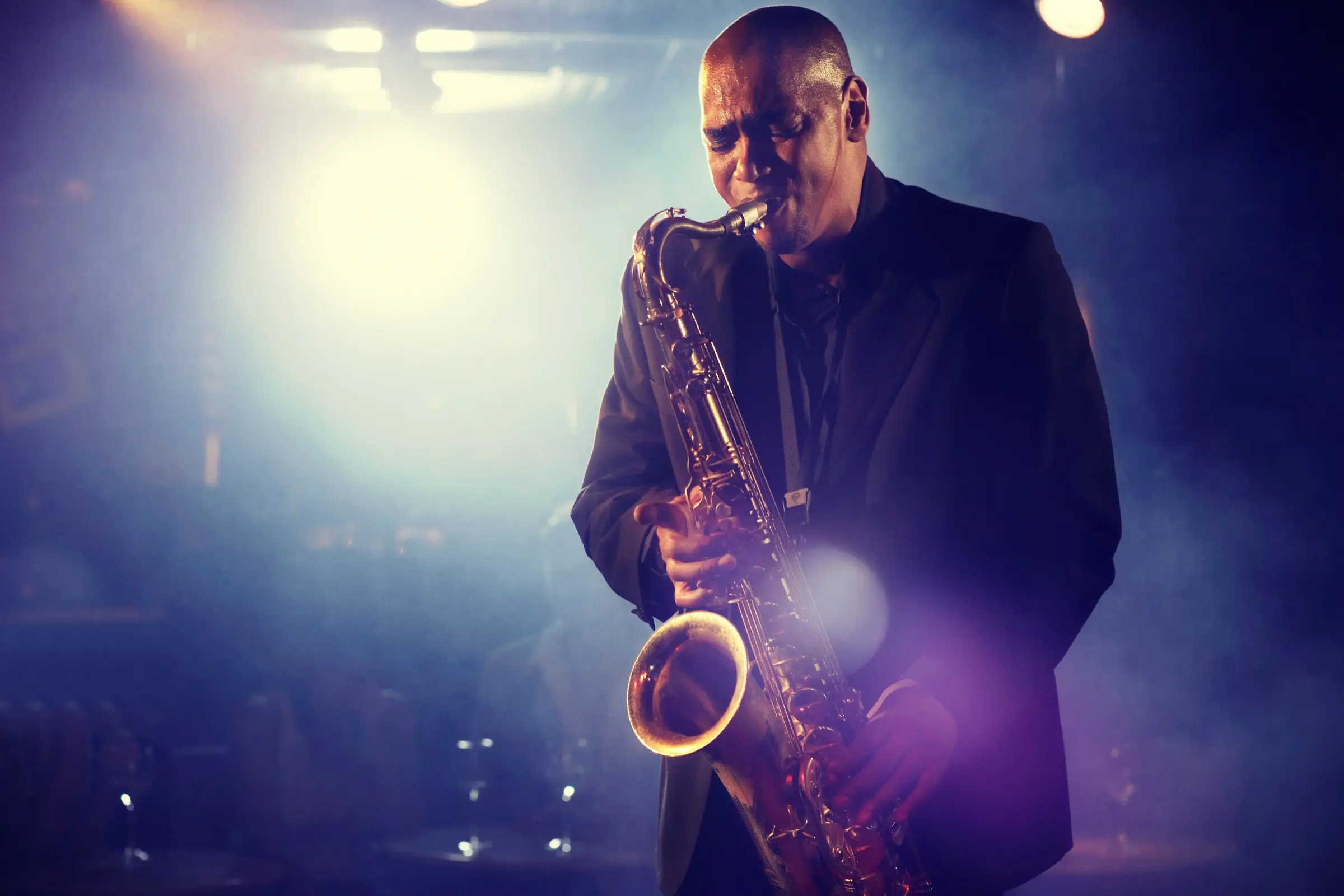 Saxophonist playing under a stage spotlight