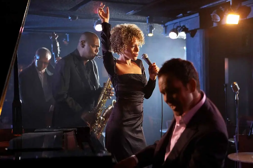 Singer performing on stage with a saxophonist and pianist