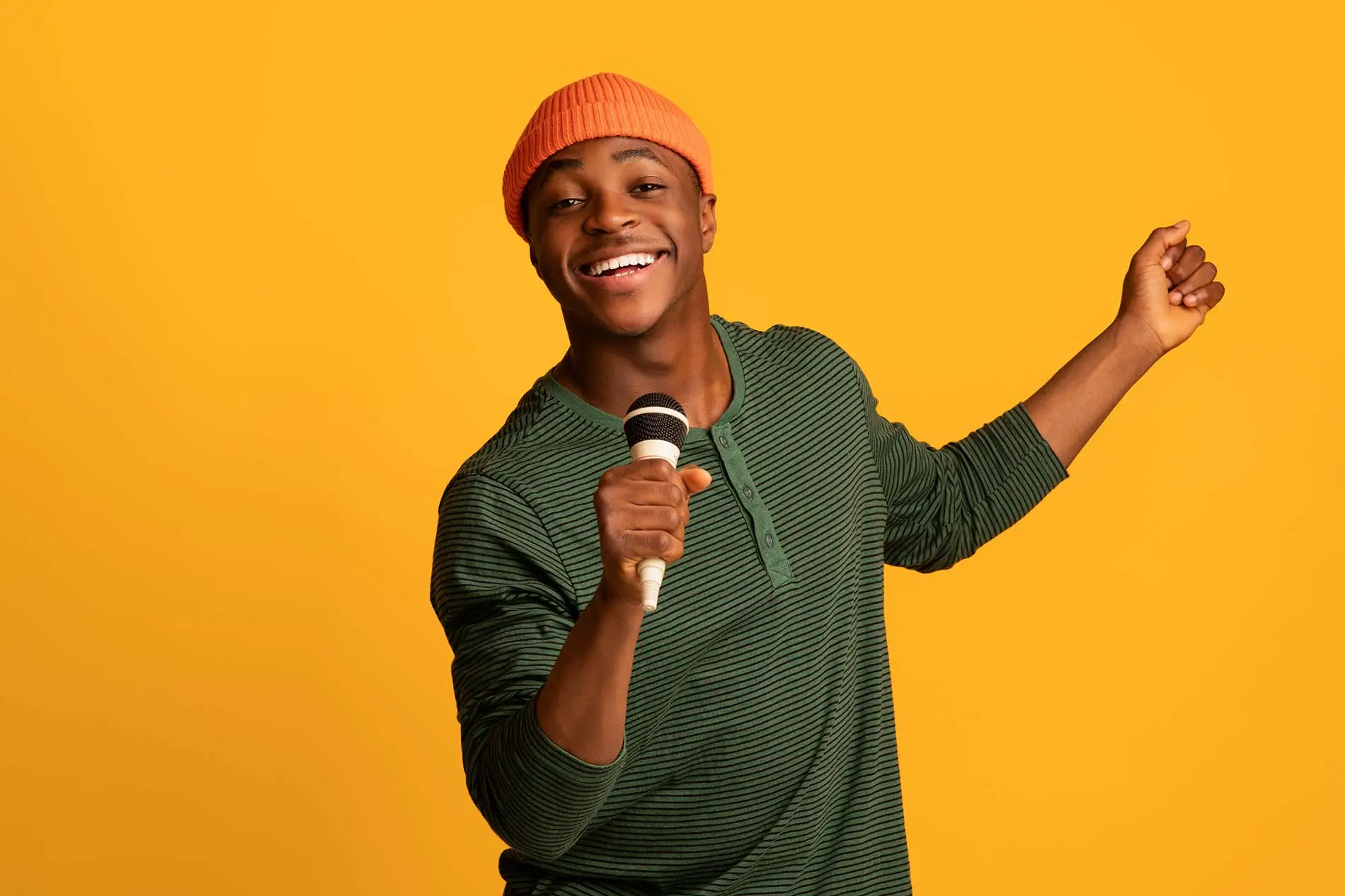 Cheerful black man holding microphone and singing