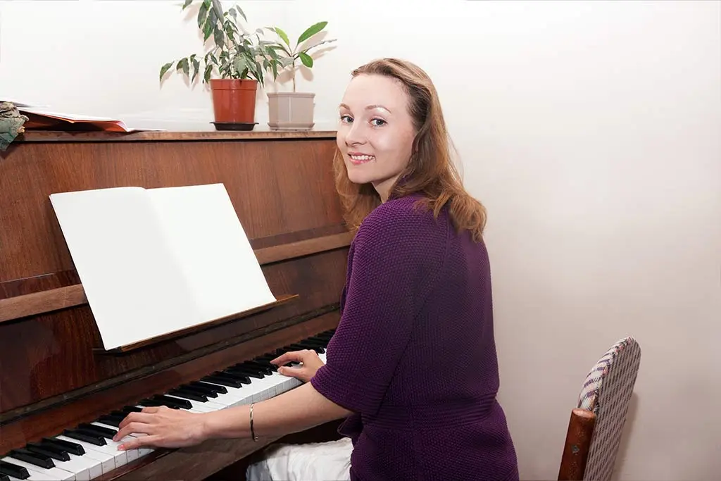 Smiling woman with hands on the piano keyboard
