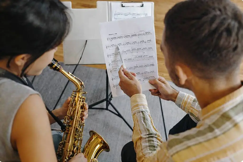 Teacher points to sheet music beside an alto saxophonist