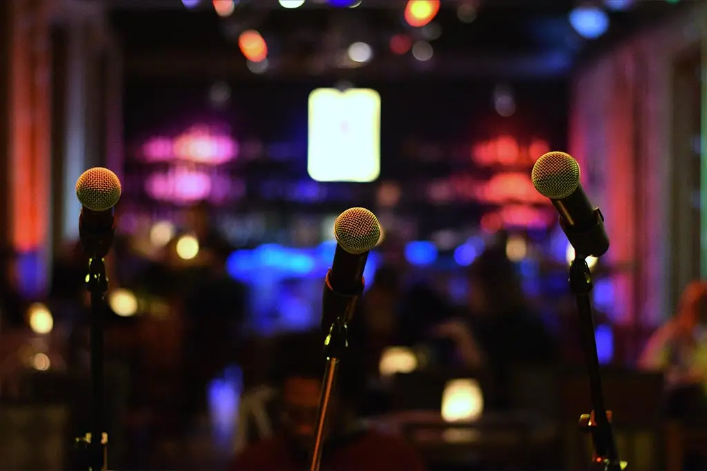 Three microphones on stands in a dimly lit venue