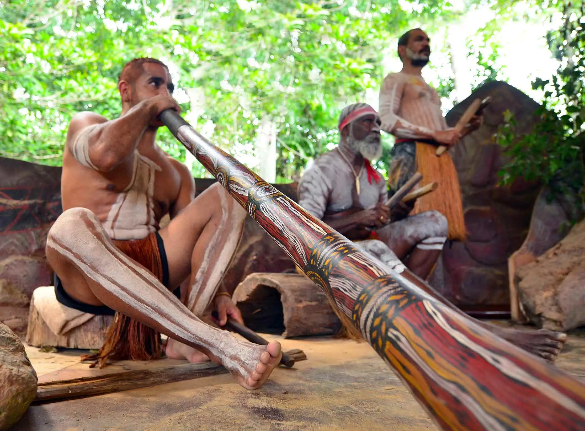 Tribal men playing music on didgeridoo
