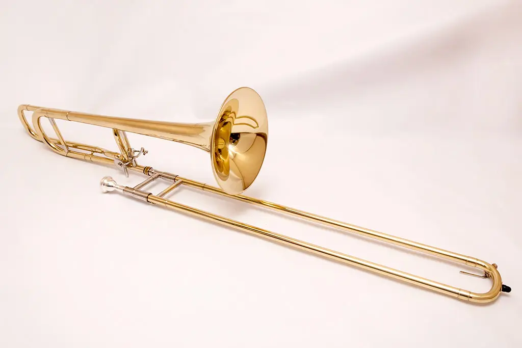 Brass trombone resting on a white fabric background