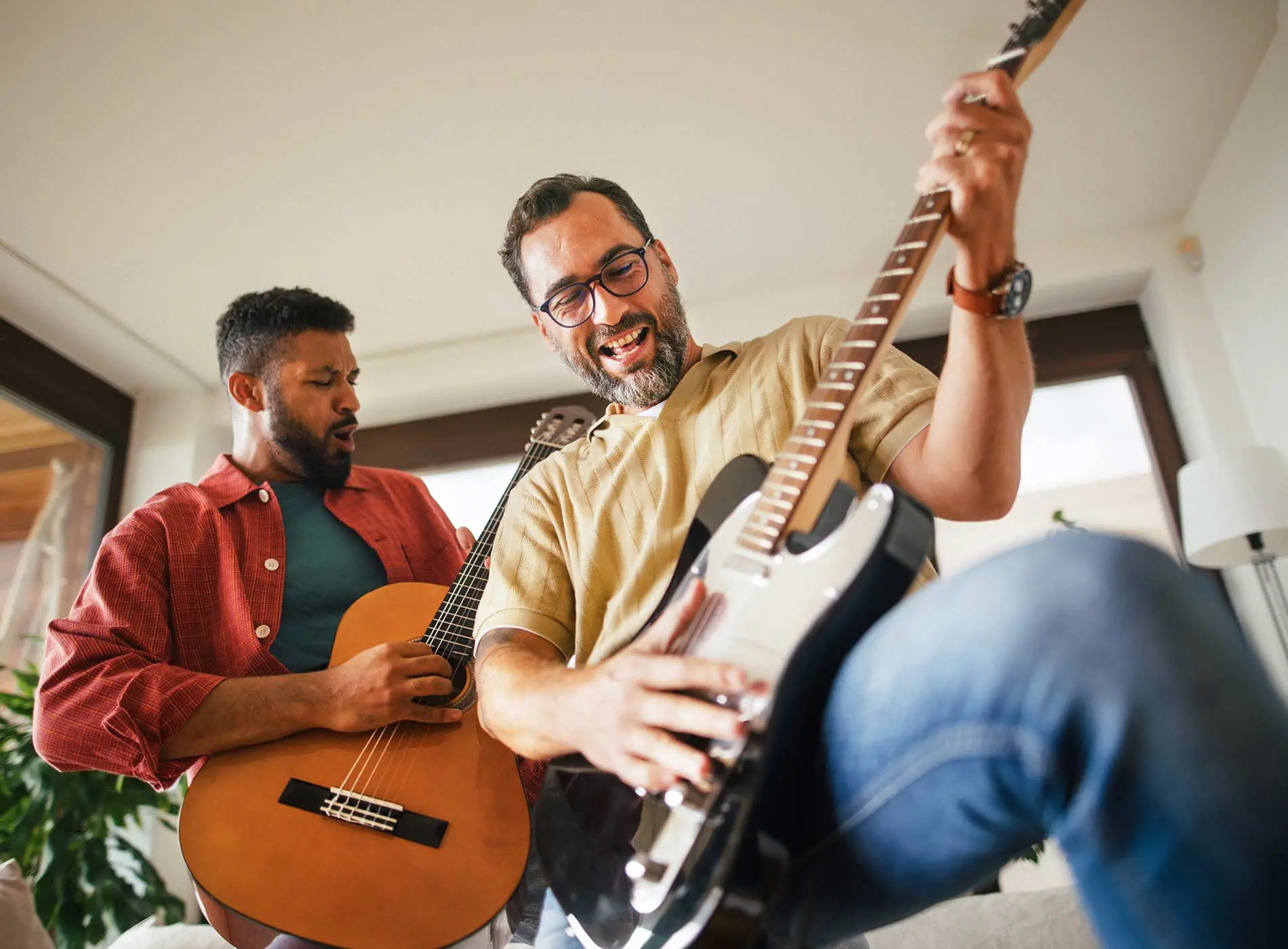 Two adult men enjoying playing the guitar