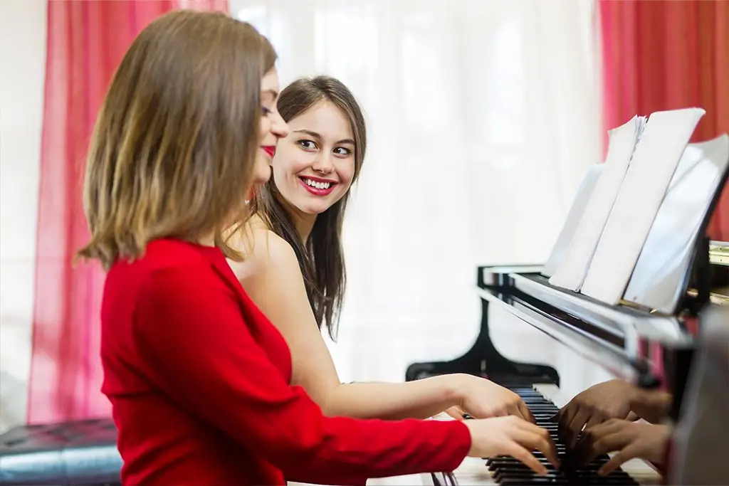Two women playing piano together