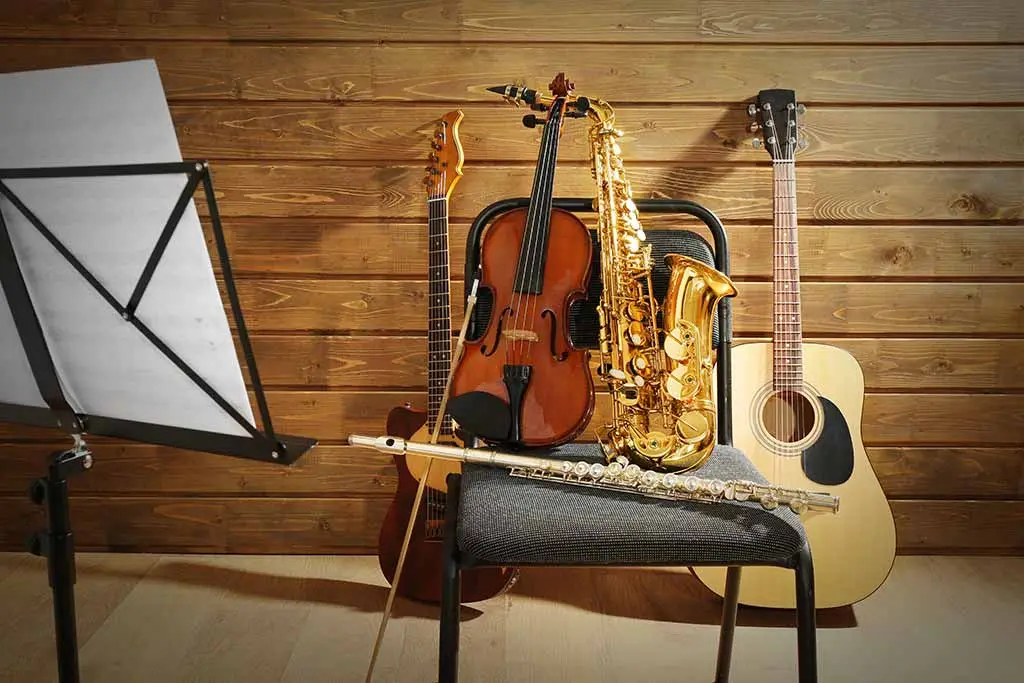 Violin, saxophone and acoustic guitar resting by a music stand