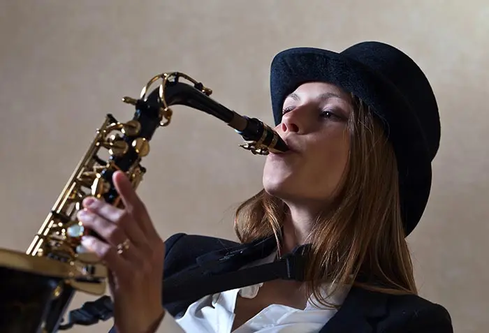 Woman in a black hat playing a saxophone