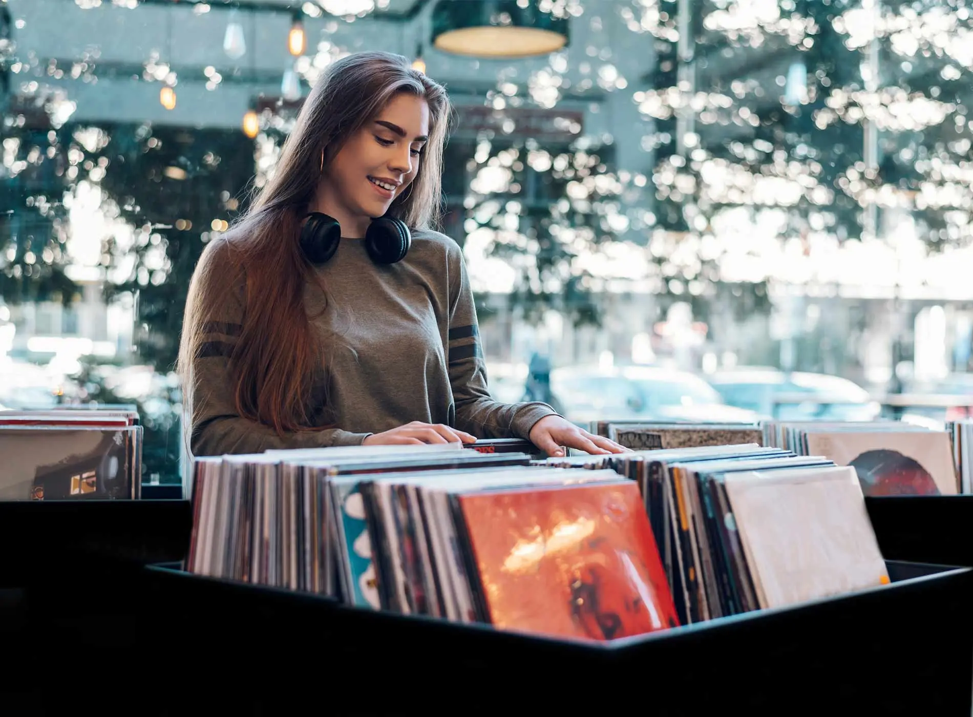Beautiful woman with headphones in a vinyl store choosing records