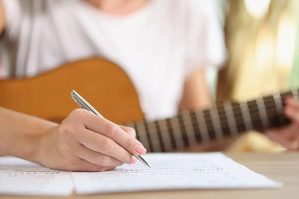 Woman composing music holding guitar