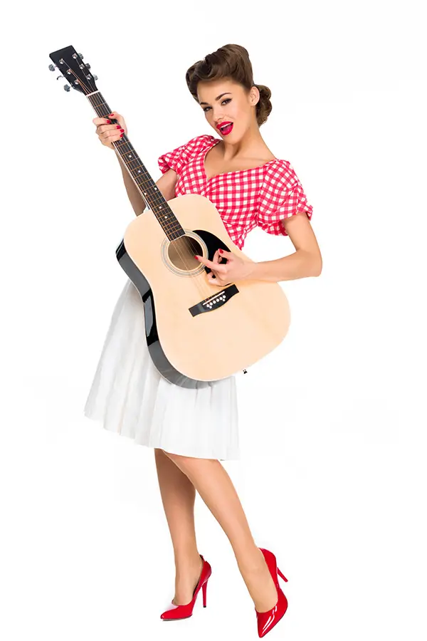 Woman in a red gingham top holding an acoustic guitar