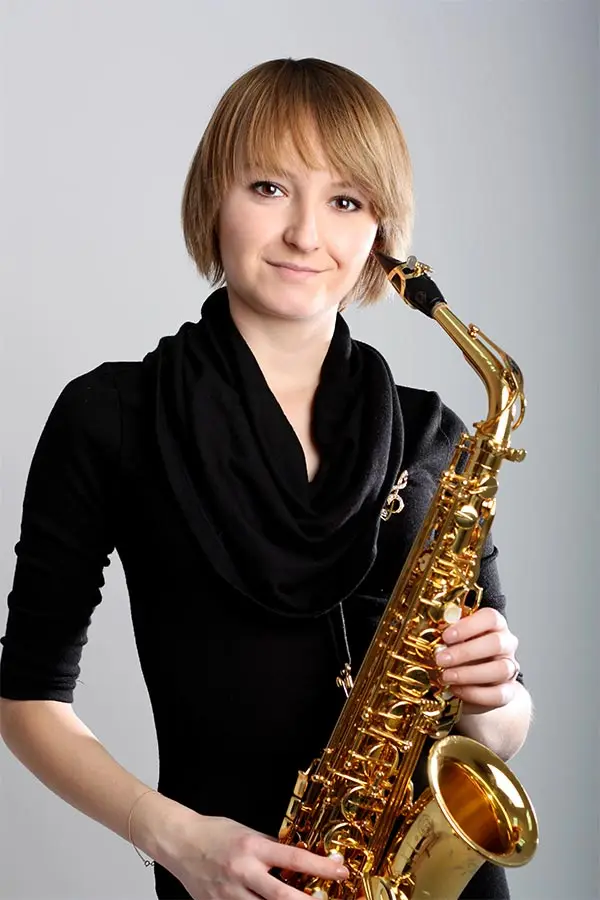 Woman in a black scarf holding an alto saxophone