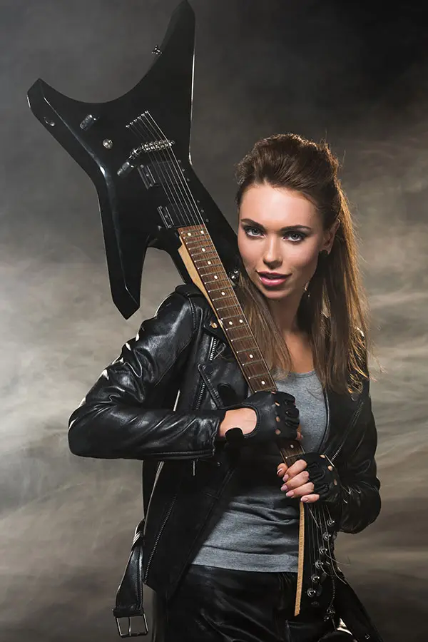 Woman in a leather jacket holding a black electric guitar