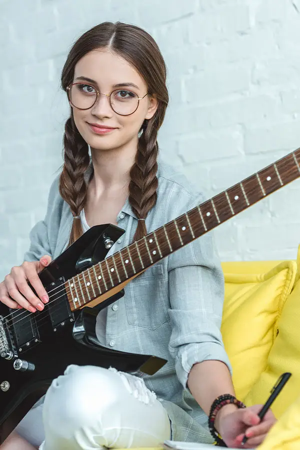 Woman with an electric guitar holding a pen