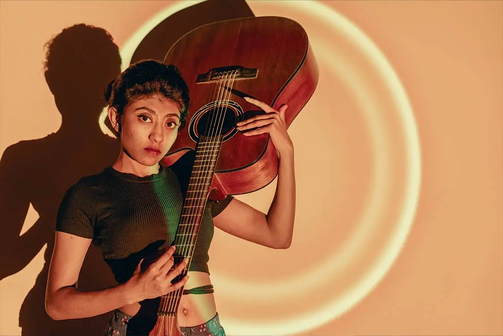 Young woman holding an upside-down acoustic guitar
