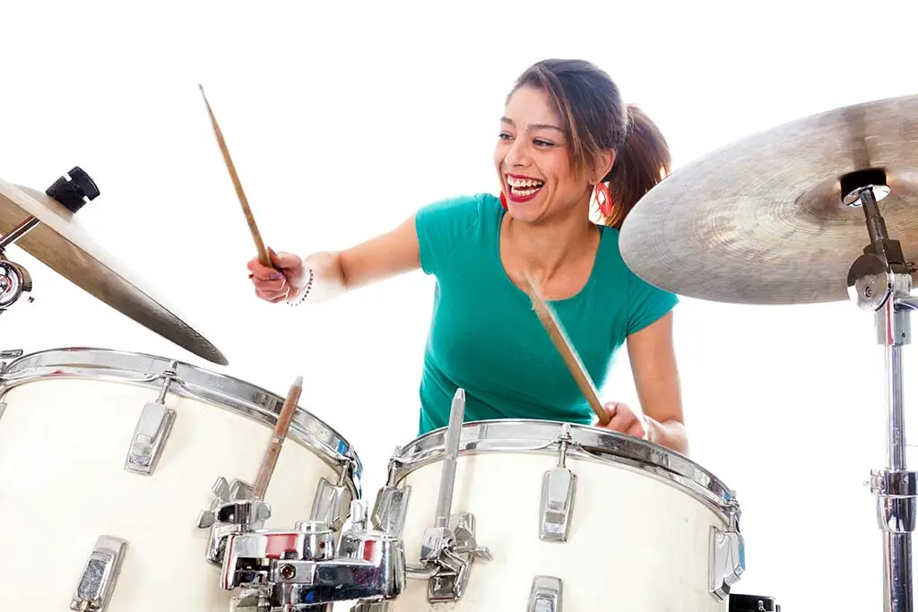 Smiling woman in a green shirt playing a drum kit