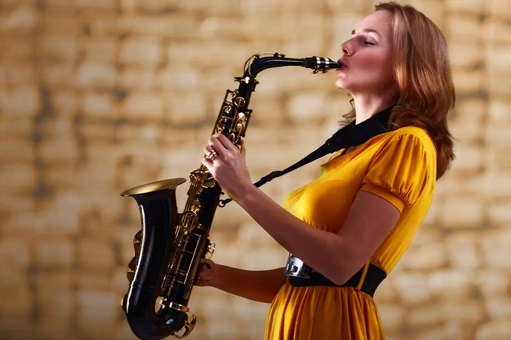Woman in yellow dress soulfully playing the saxophone