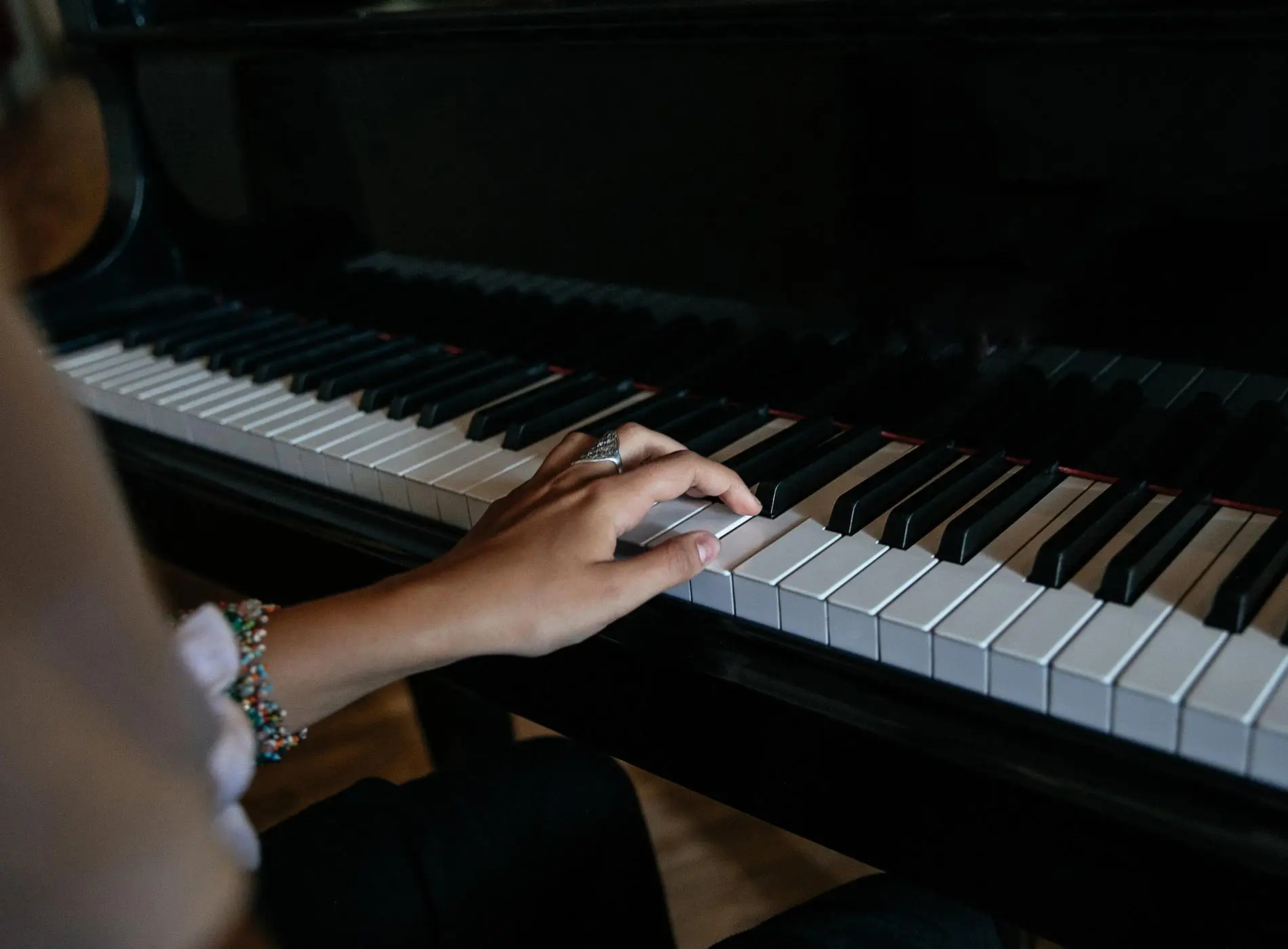 Woman left hand on piano keyboard