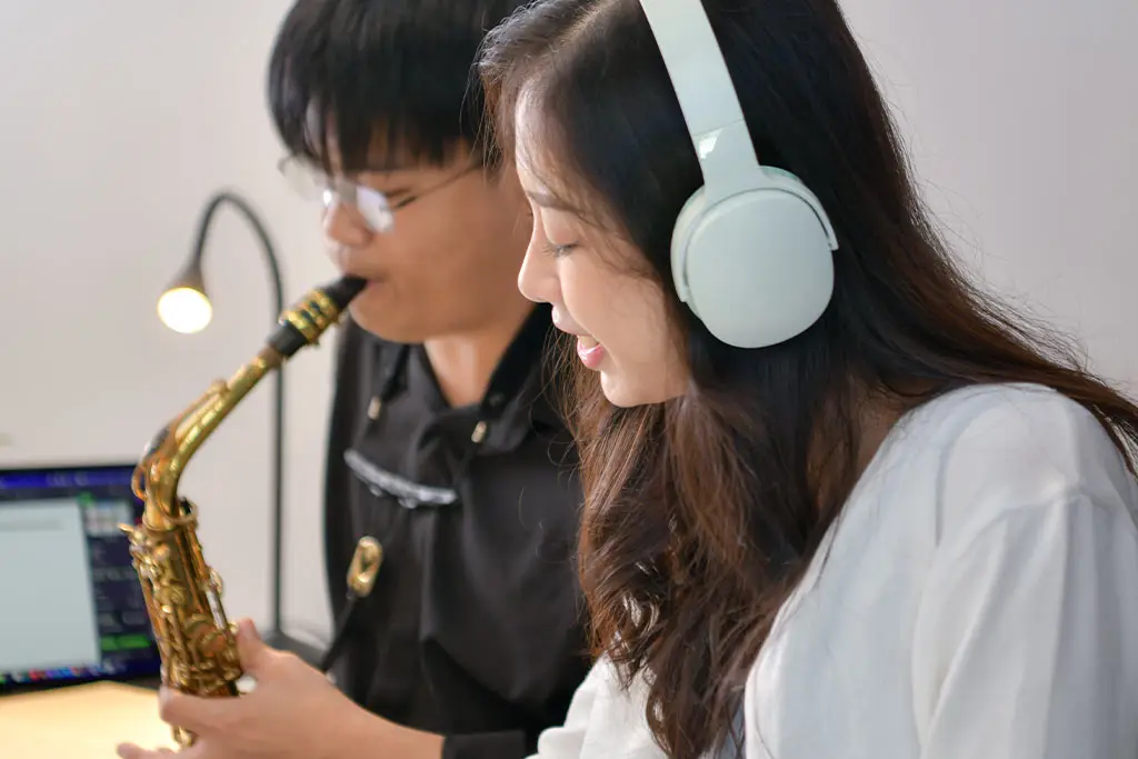 Woman wearing headphones beside a man playing alto saxophone